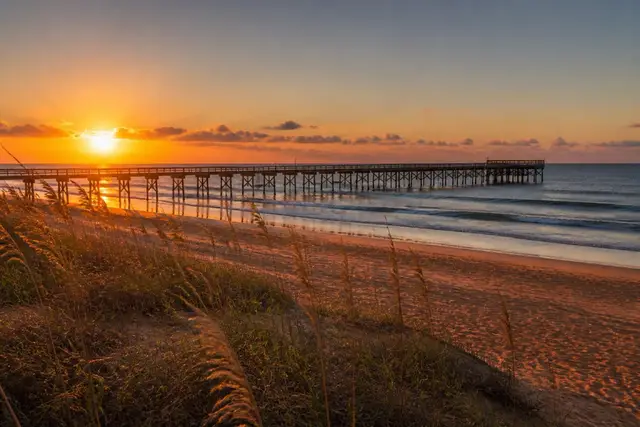 Cinnamon-colored coquina sand at Flagler Beach at golden hour with a weathered wooden pier in the distance